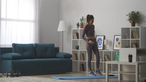 young-woman-is-training-alone-in-living-room-and-taking-break-workout-at-home-during-self-isolation-and-quarantine-keeping-fit-and-health